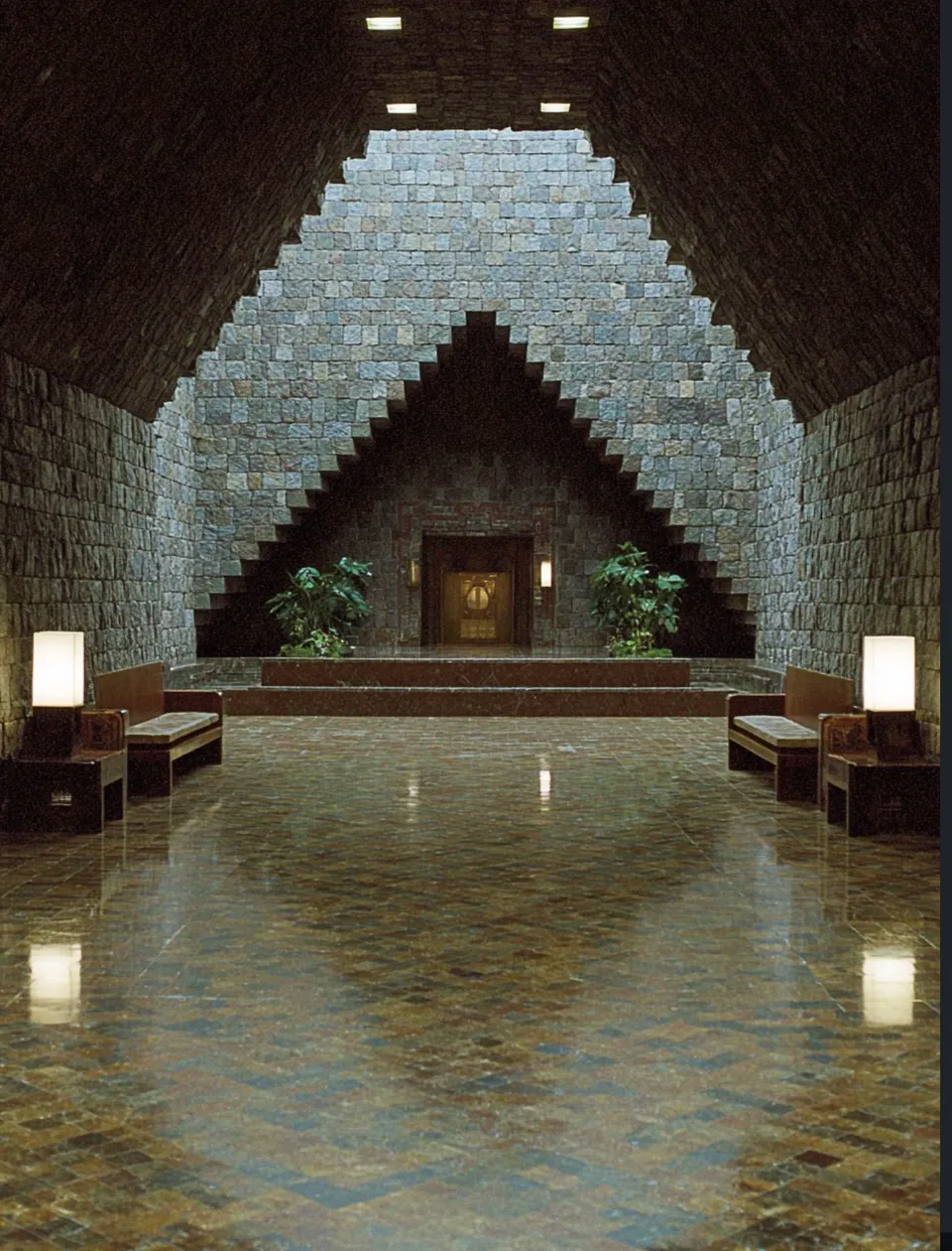 Recibidor de piedra con arcos escalonados y espejo de agua